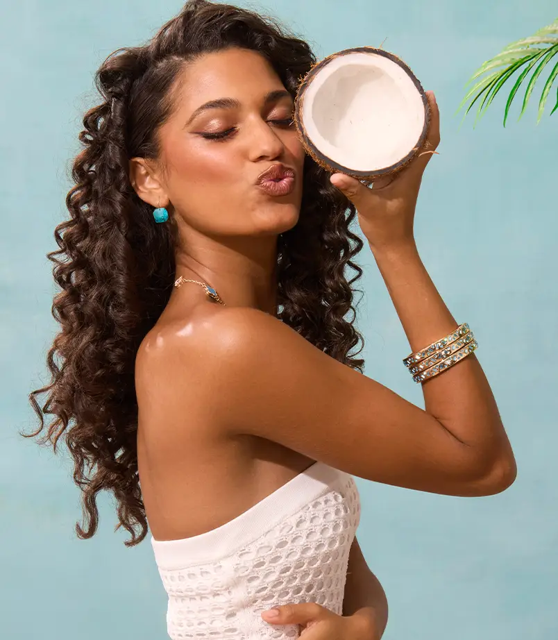 Model wearing Gold heart jewelry leaning against the wall
