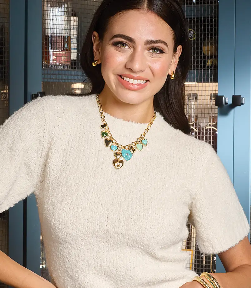Model showcasing a colorful gold charm necklace with turquoise and gemstone pendants