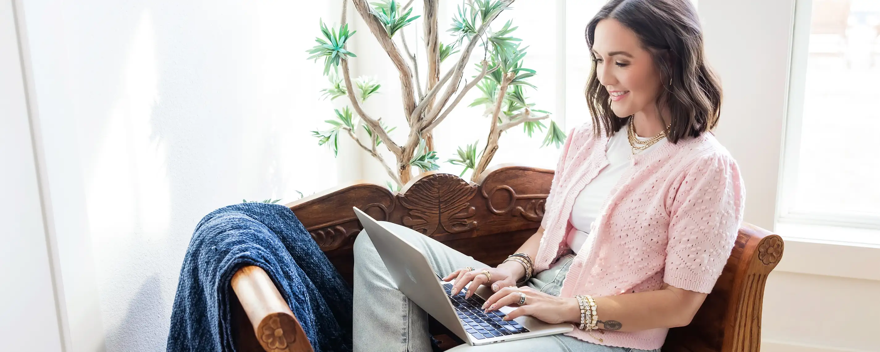 Woman sitting infront of bright windows, working on her laptop
